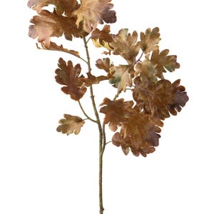May include: A decorative artificial branch featuring multiple oak leaves in shades of brown, tan, and muted green. The leaves have a textured, weathered appearance with visible veins and serrated edges, attached to a thin, straight brown stem.
