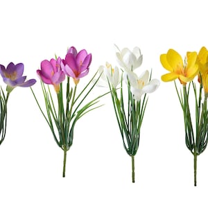 May include: A bouquet of artificial crocuses in purple, pink, white, and yellow. The flowers are arranged in a bunch with green stems and leaves.