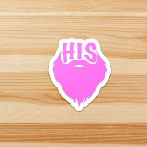 May include: Two pink stickers with a beard and the word "HIS" on top. The stickers are on a light brown wooden surface.