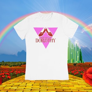 May include: White t-shirt with a pink triangle graphic featuring red ruby slippers and the text "Friends of Dorothy".