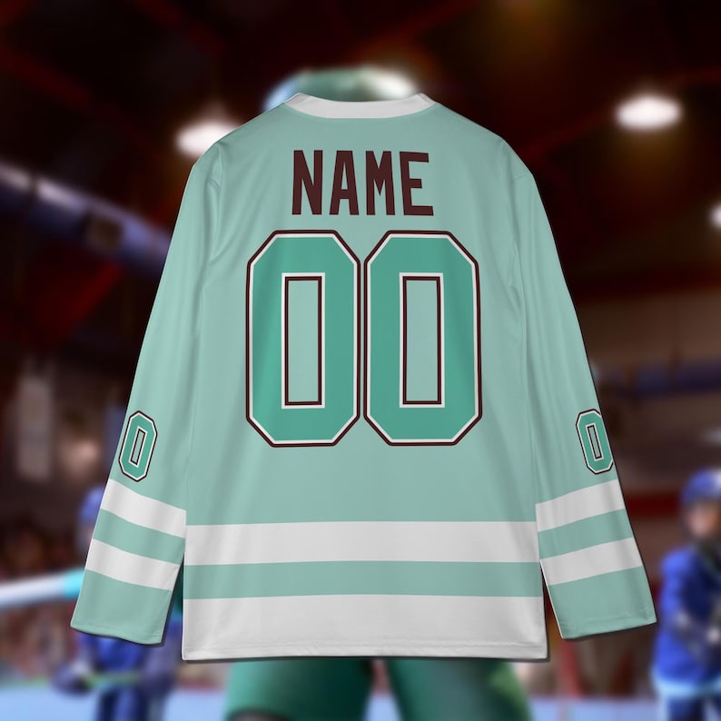 Puede incluir: Una camiseta de hockey azul claro con rayas blancas y detalles marrones. La camiseta tiene el n&uacute;mero "00" y la palabra "NAME" impresa en la espalda.
