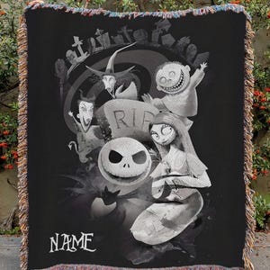 May include: Black and white throw blanket featuring characters from a Tim Burton movie. The blanket has a fringe border with multiple colors. The word "NAME" is printed on the bottom of the blanket.