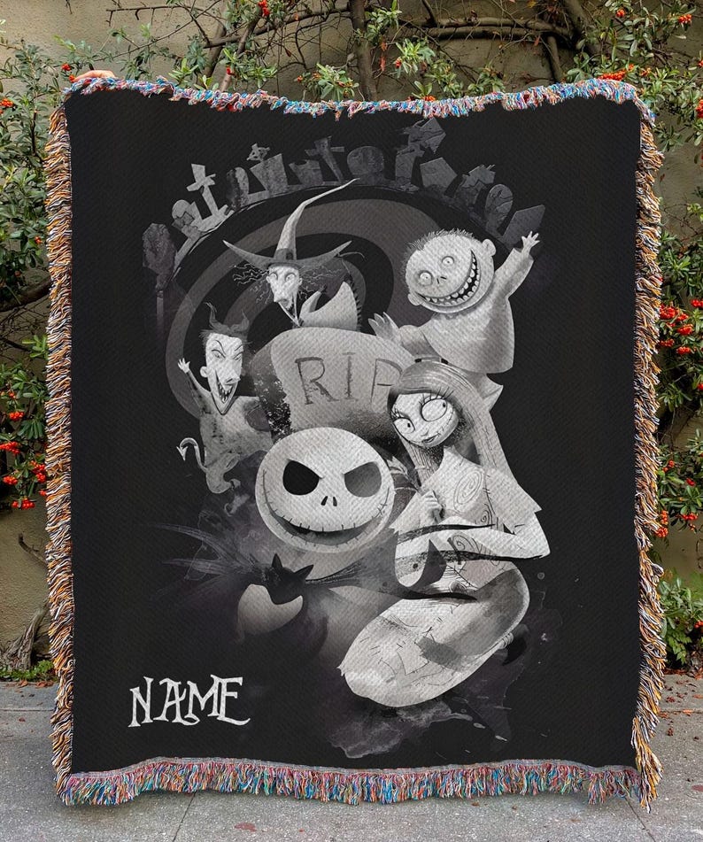 May include: Black and white throw blanket featuring characters from a Tim Burton movie. The blanket has a fringe border with multiple colors. The word "NAME" is printed on the bottom of the blanket.