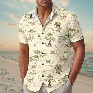 May include: A short-sleeve button-down shirt in a cream color featuring a repeating map print of the Hundred Acre Wood. The design includes illustrations of trees, paths, and characters with text labels like 100 Aker Wood and Bee Tree.