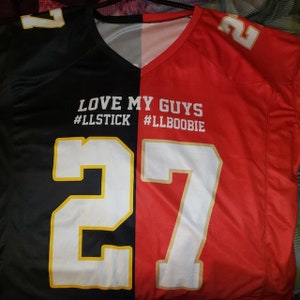 May include: A black and red football jersey with the number 27 on each side. The jersey has the text "LOVE MY GUYS #LLSTICK #LLBOOBIE" printed on the front.