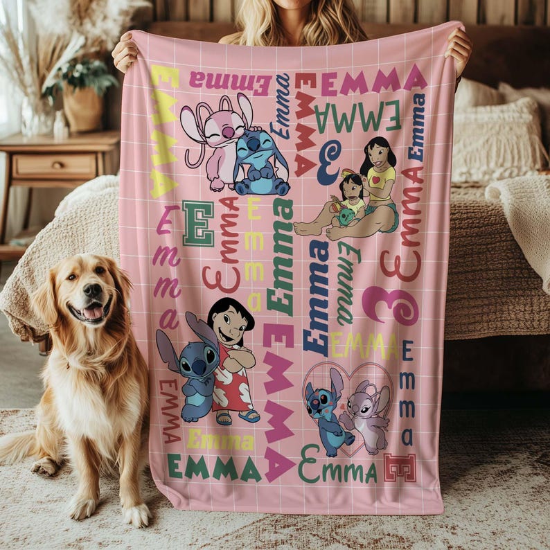 May include: Pink fleece blanket featuring cartoon characters and the name "Emma" in various colors and fonts. The blanket has a grid pattern and includes images of Stitch and Lilo. A golden retriever dog is in the foreground.