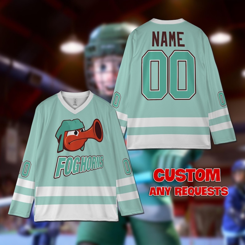 Puede incluir: Una camiseta de hockey de color verde azulado y blanco con un personaje de dibujos animados rojo y blanco con un cuerno en la parte delantera. La camiseta tiene el texto "FOGHORNS" en la parte delantera. La parte posterior de la camiseta tiene el texto "NAME" y "00" en verde azulado.