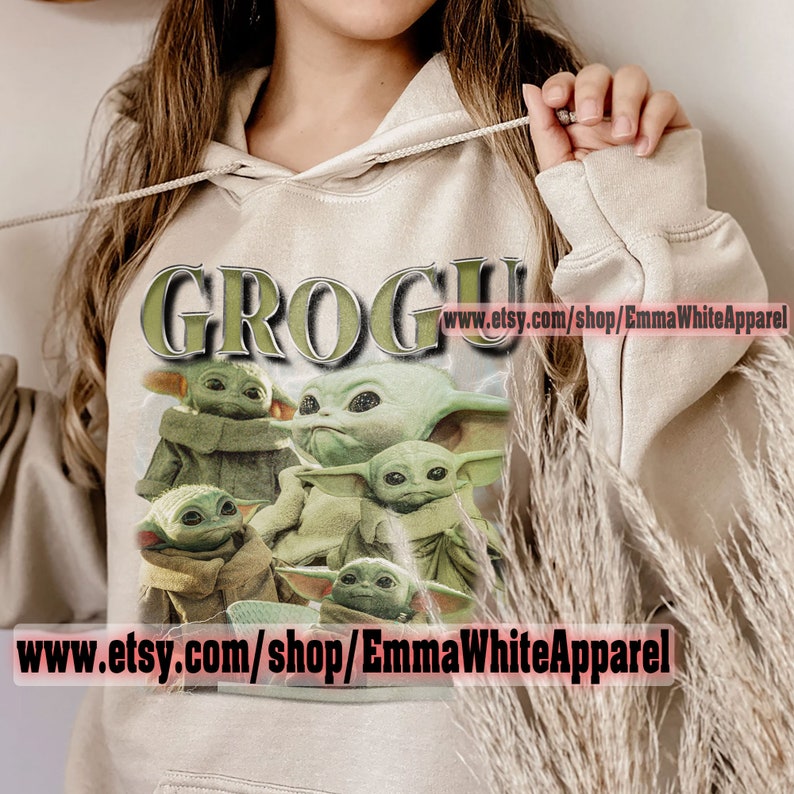 May include: A beige hoodie with a graphic print of multiple green "Grogu" characters from the Star Wars series. The text "Grogu" is printed in green and white letters on the hoodie. The text "www.etsy.com/shop/EmmaWhiteApparel" is printed on the hoodie.