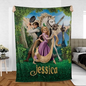 May include: A plush blanket featuring a scene from the animated movie, Tangled. The design includes characters Rapunzel, Flynn Rider, and Maximus, with a castle in the background. The name "Jessica" is written in gold script at the bottom.