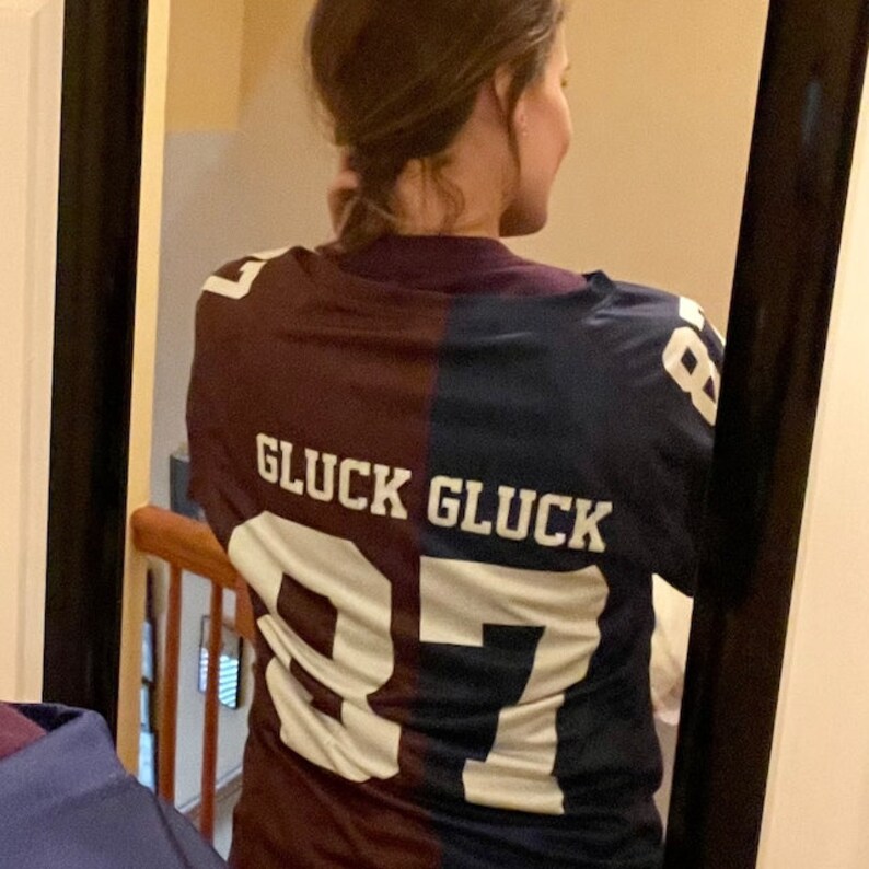 May include: A maroon and navy blue jersey with the text "GLUCK GLUCK" and the numbers "87" on the back.