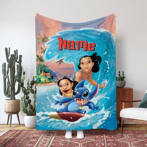 Op de afbeelding: Een blauwe deken met een levendige illustratie van Lilo & Stitch die op een golf surfen. De deken heeft een tropische strandachtergrond met het woord "Name" in het rood. De personages staan op de voorgrond, met Stitch op een surfplank.