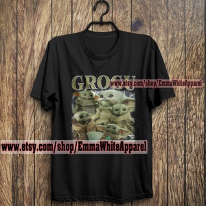 May include: Black t-shirt with a graphic of multiple green "Grogu" characters from the Star Wars series. The text "GROGU" is printed in gold letters above the characters. The text "www.etsy.com/shop/EmmaWhiteApparel" is printed at the bottom of the shirt.