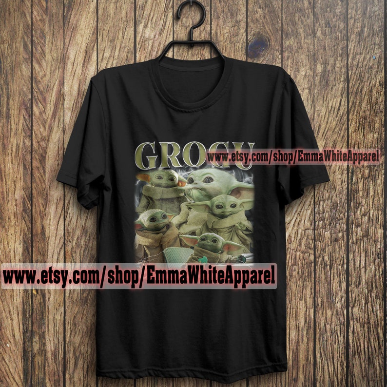 May include: Black t-shirt with a graphic of multiple green "Grogu" characters from the Star Wars series. The text "GROGU" is printed in gold letters above the characters. The text "www.etsy.com/shop/EmmaWhiteApparel" is printed at the bottom of the shirt.