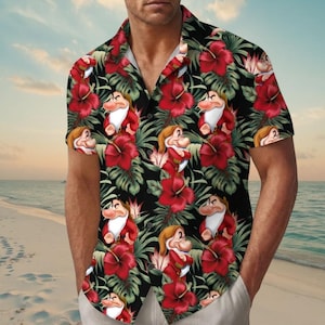 Puede incluir: Una camisa de manga corta con botones en la parte delantera, con un fondo negro y un patrón repetitivo de flores de hibisco rojas, hojas tropicales verdes y el personaje Gruñón con un gorro y una túnica de color rojo.