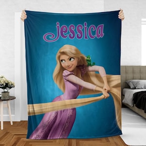 May include: A blue fleece blanket featuring a cartoon illustration of a princess with long blonde hair and a green frog. The name "Jessica" is written in a cursive font at the top of the blanket.
