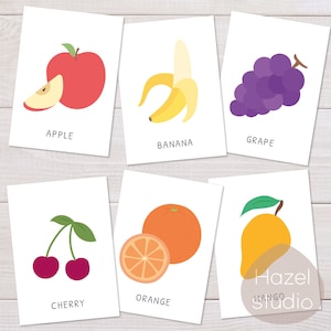 Puede incluir: Flashcards con ilustraciones de diferentes frutas: una manzana roja, un pl&aacute;tano amarillo, un racimo de uvas moradas, una cereza roja, una naranja naranja y un mango amarillo. El texto debajo de cada fruta es el nombre de la fruta.