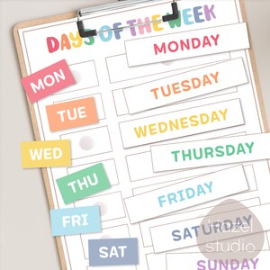 May include: A printable chart with the days of the week written in colorful text. The days of the week are written in a rainbow color scheme. The chart is on a clipboard.