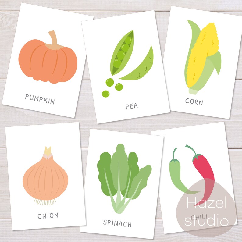 Op de afbeelding: Zes printbare flashcards met illustraties van verschillende groenten, waaronder een pompoen, erwten, ma&iuml;s, een ui, spinazie en chilipepers. Elke kaart heeft de naam van de groente onder de illustratie.