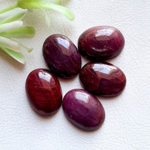 以下が含まれることがあります： 紫がかった深紅色の、滑らかで磨かれた5つの楕円形の宝石。