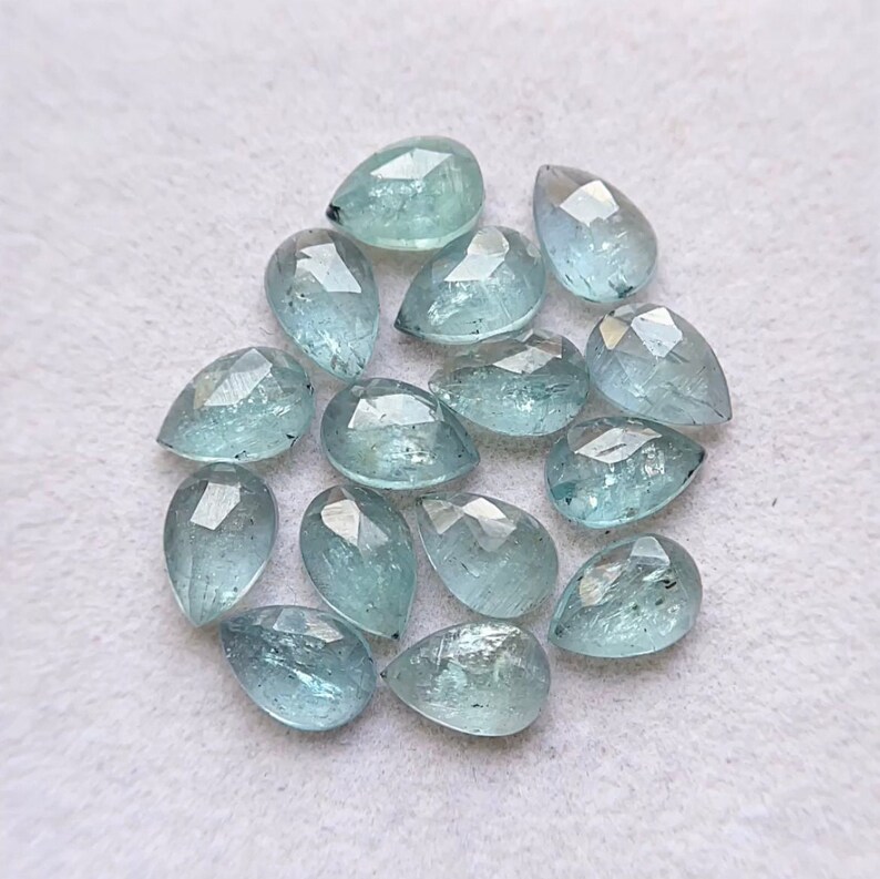 Puede incluir: Una colecci&oacute;n de 15 piedras preciosas de aguamarina en forma de pera. Las piedras son de color azul claro y tienen un corte facetado.