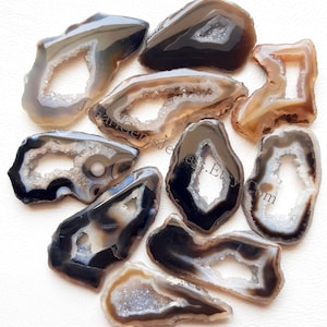 May include: Ten agate slices with natural crystal formations and a variety of brown and black colours. Each slice has a unique shape and a hole in the centre.