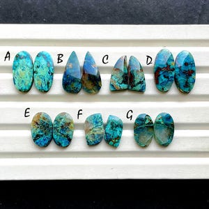 May include: A selection of seven pairs of polished gemstones in different shapes. The stones exhibit a mix of teal, blue, and brown colours, with unique patterns and textures. Each pair is labelled with a letter from A to G.