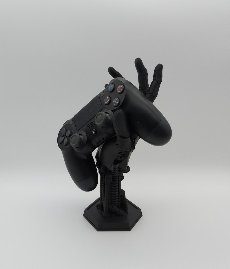 Controller Halterung im Alien-Hand Design. Farbe Schwarz. Es liegt ein PS5 Controller auf der Hand. Science Fiction Stil