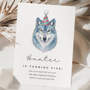 Puede incluir: Una invitación de cumpleaños con una ilustración en acuarela de un lobo con un gorro de fiesta. El texto dice "¡Hunter cumple cinco años!" con los detalles del evento debajo. La invitación está sobre un fondo blanco.