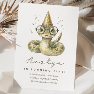 Puede incluir: Una invitación de cumpleaños con una ilustración en acuarela de una serpiente con gafas y un gorro de fiesta. La invitación dice "¡Austyn cumple cinco años!" con los detalles del evento a continuación. Confeti esparcido alrededor de la serpiente.