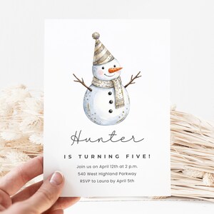 Op de afbeelding: Een witte uitnodigingskaart met een aquarel illustratie van een sneeuwpop met een gestreepte hoed en sjaal. De tekst "Hunter IS TURNING FIVE!" wordt in elegant schrift weergegeven, samen met de evenementdetails.
