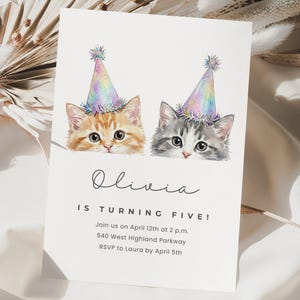 May include: A white birthday invitation featuring two watercolor kittens wearing party hats. The text "Olivia IS TURNING FIVE!" is displayed below the kittens, along with event details. The invitation is designed with a whimsical and celebratory theme.