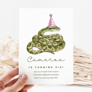 May include: A birthday invitation featuring a watercolor illustration of a green snake wearing a pink party hat. The text reads "Cameron IS TURNING SIX!" with event details below. The invitation is held by a hand.