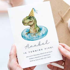 Peut inclure: Une invitation d'anniversaire avec une illustration à l'aquarelle d'un dinosaure vert portant un chapeau de fête et flottant dans une bouée bleue. Le texte dit : "Anabel fête ses cinq ans !" avec les détails.