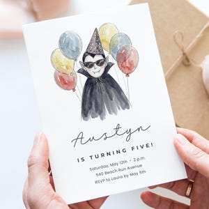 May include: A white birthday invitation card featuring a watercolor illustration of a vampire wearing sunglasses and a party hat, surrounded by colorful balloons. The text reads: Austyn IS TURNING FIVE! Saturday, May 12th, 2 p.m., 540 Beach Run Avenue, RSVP to Laura by May 5th.