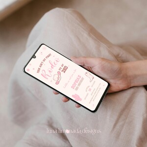 K&ouml;nnte beinhalten: Ein Smartphone mit einer digitalen Geburtstagseinladung in Rosa und Wei&szlig; mit dem Text "THIS AIN'T MY FIRST RODEO IT'S MY 2ND", "SADDLE UP AND JOIN US FOR SOPHIA'S 2ND BIRTHDAY", "SEPTEMBER 28", "12:00-3:00PM" und "123 ANYWHERE AVE, ANYWHERE, ST 12345".