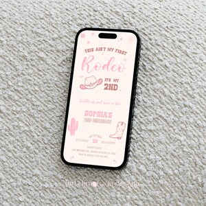 K&ouml;nnte beinhalten: Ein Smartphone mit einer digitalen Einladung in Rosa f&uuml;r einen zweiten Geburtstag. Der Text lautet: This ain't my first rodeo, it's my 2nd, Sophia's 2nd birthday, 28. September, 17:00 Uhr, inklusive Grafiken von Cowboyhut, Kaktus und Stiefel.