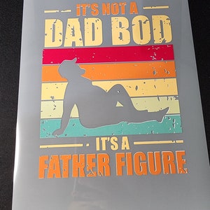 May include: A gray background with a vintage-style graphic that says "It's not a Dad Bod. It's a Father Figure." The graphic features a silhouette of a person sitting with a retro sunset design behind them.