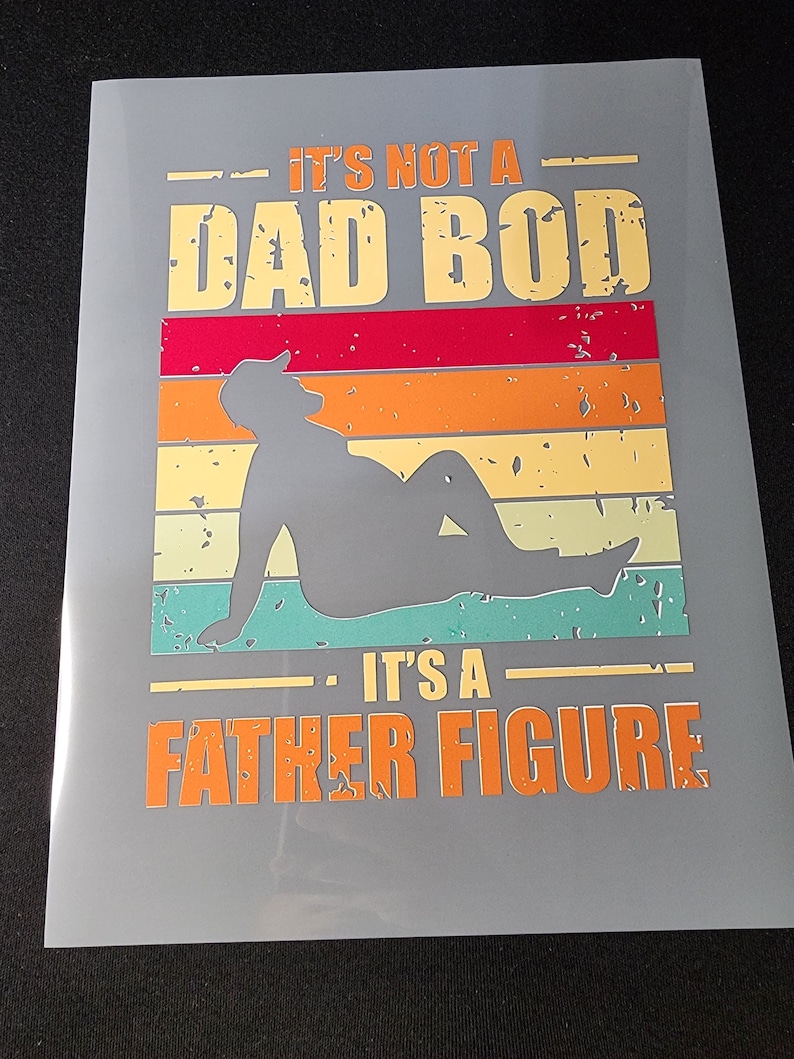 May include: A gray background with a vintage-style graphic that says "It's not a Dad Bod. It's a Father Figure." The graphic features a silhouette of a person sitting with a retro sunset design behind them.