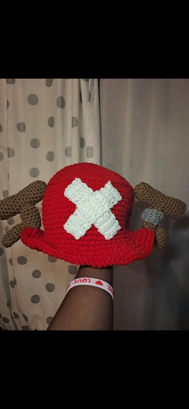 K&ouml;nnte beinhalten: Ein handgeh&auml;kelter Hut im Stil von Tony Tony Chopper aus dem Anime One Piece. Der Hut ist haupts&auml;chlich rot mit einem wei&szlig;en Kreuz auf der Vorderseite und braunen und grauen Akzenten. Ein lustiges Accessoire f&uuml;r Cosplay oder Fans.