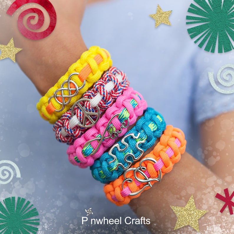 May include: A stack of six colorful friendship bracelets with different charms, including a peace sign, infinity symbol, and a heart. The bracelets are made with paracord and are a fun and trendy accessory.