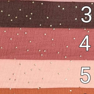May include: Seven fabric swatches with a subtle sparkle. The swatches are in shades of green, pink, brown, red, light pink, orange, and burgundy.