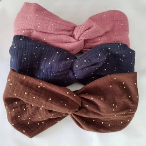 May include: Three fabric headbands in brown, navy blue, and pink with gold glitter dots. The headbands are twisted and knotted.