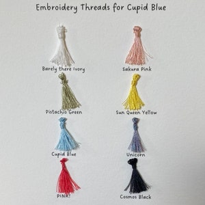 May include: Embroidery threads in various colors, including barely there ivory, sakura pink, pistachio green, sun queen yellow, cupid blue, unicorn, pink, and cosmos black. The threads are arranged in a grid on a white background.