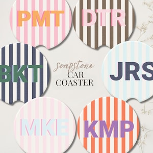 May include: Six round car coasters with striped patterns in various colors, including pink, brown, blue, and orange. Each coaster features a different three-letter initial in a contrasting color. The text "soapstone CAR COASTER" is also present.