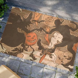 May include: A rectangular doormat featuring a vintage-style Halloween illustration in shades of brown, orange, and cream. The design depicts silhouettes of a witch and a devil dancing with a jack-o'-lantern, a ghost, and a crescent moon face.