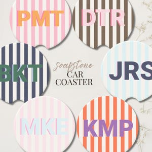 May include: Six circular soapstone car coasters featuring vertical stripes in various colors including pink, brown, navy, light blue, and orange. Each coaster displays a three-letter monogram in contrasting colors. The text soapstone CAR COASTER is centered.