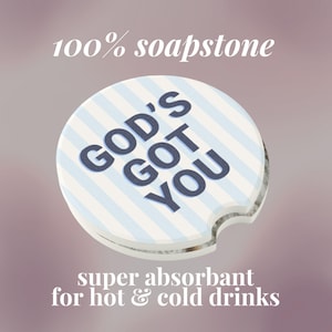 May include: A round, white soapstone car coaster with blue and white stripes and the text "GOD'S GOT YOU" in navy blue. The coaster is super absorbent for hot and cold drinks.