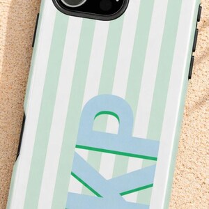 Może przedstawiać: Etui na telefon z miętowo-zielonym i białym wzorem w paski. Etui posiada jasnoniebieskie inicjały "KP" oraz adres strony internetowej THEBELLEJOLIE.ETSY.COM.