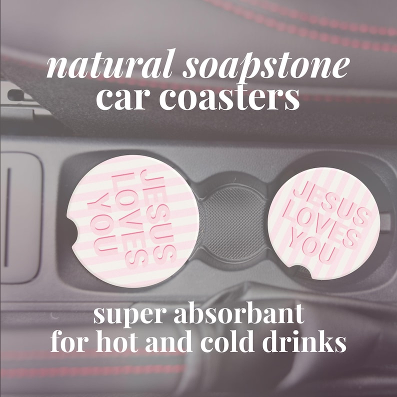 May include: Two natural soapstone car coasters with the text "JESUS LOVES YOU" in pink. The coasters are round with a striped pattern and are designed to absorb moisture from hot and cold drinks. The image also includes the text "super absorbant for hot and cold drinks".