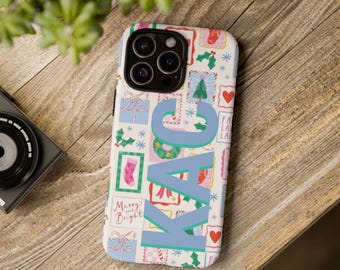 May include: A white smartphone case featuring a repeating pattern of colorful holiday icons including gift boxes, stockings, wreaths, and snowflakes, with the large blue letters KAC printed vertically across the center and the text Merry and Bright.
